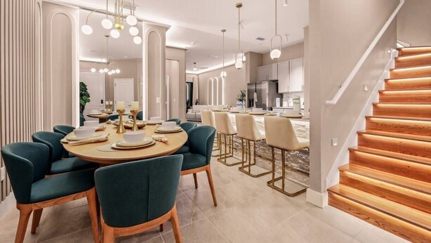 A modern dining area with a round table, teal chairs, and pendant lighting. - Modern 5BR Villa w/ Pool – 15 min to Disney (Orlando)