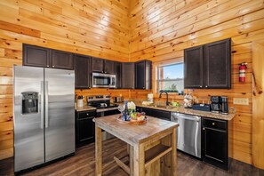 Cocina de cabaña de madera con refrigerador de acero inoxidable, microondas y cafetera.