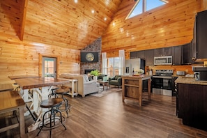 Ein geräumiges Holzblockhaus-Interieur mit Küche, Essbereich und Wohnzimmer.