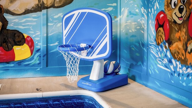 Ein Poolbereich mit einem blauen und weißen Basketballkorb, einem Poolball und einem Wandgemälde eines Bären.