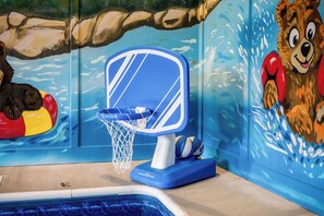 A pool area with a blue and white basketball hoop, a pool ball, and a mural of a bear. - Firefly Haven Private Indoor Pool, Hot Tub & Game Room Near Dollywood (Pigeon Forge)