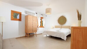Un dormitorio con cama, armario de madera, lámpara colgante y espejo instalado en la pared.