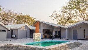 A modern house with a swimming pool, covered patio, and a gravel driveway.