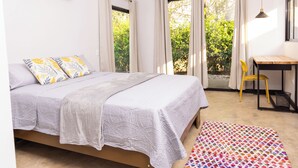A bedroom with a bed, a desk, a chair, and a window with curtains.