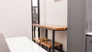 A modern kitchen with white countertops, a wooden table, and a built-in bench.