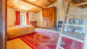 A bedroom with a bed, a wooden wardrobe, a ladder, a bookshelf, and a red patterned rug. - Bed and Breakfast 'Chambre 3' with Shared Pool, Shared Terrace and Wi-Fi (Vers Pont du Gard)