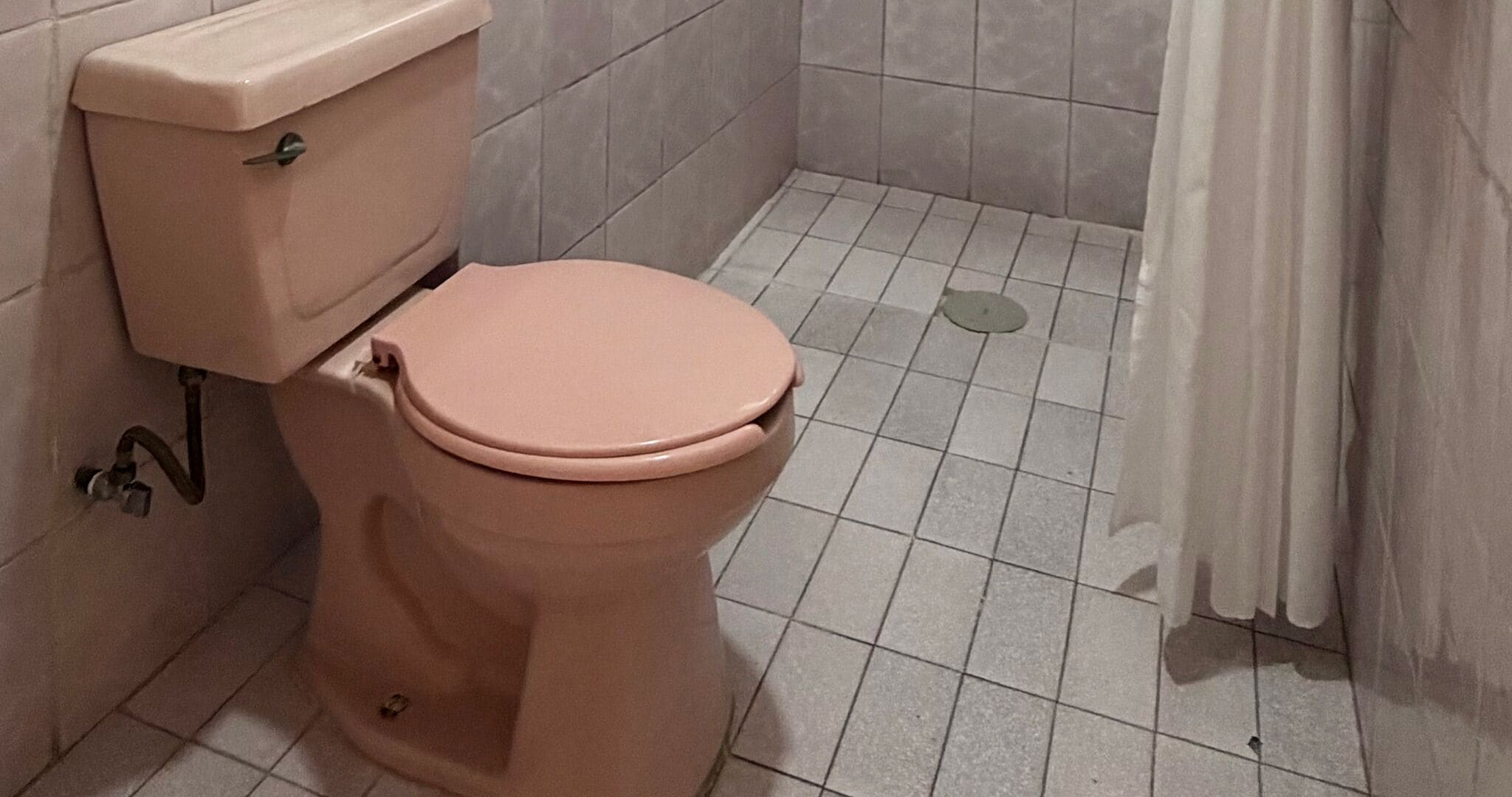 A toilet in a bathroom with tiled walls and floor.
