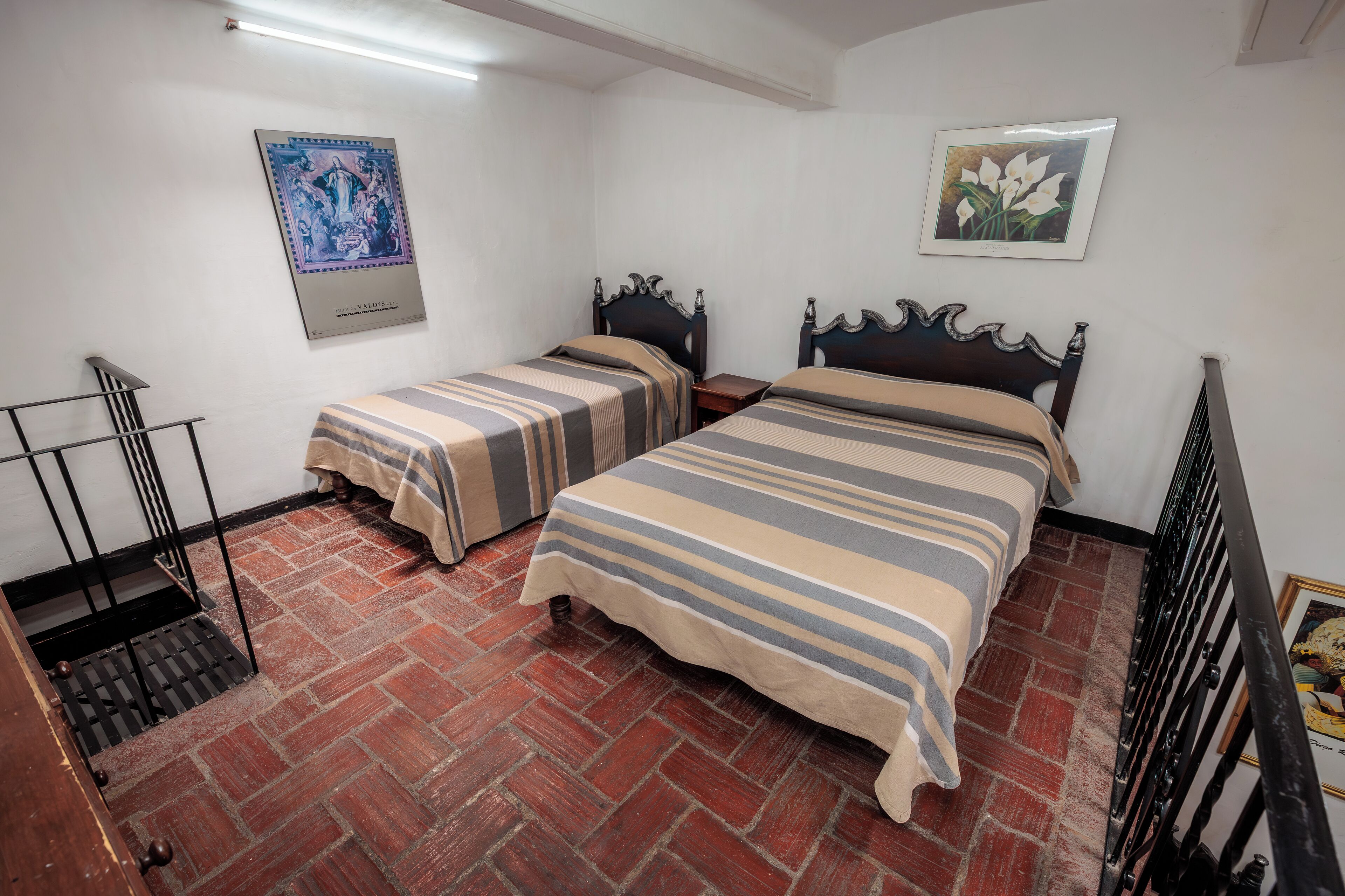 Ein Zimmer mit zwei Betten, Holzboden und einer Treppe.