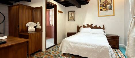 Un dormitorio con cama, armario de madera y un piso de baldosas coloridas.