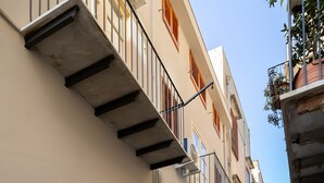 A narrow street with buildings featuring balconies and a wooden door. - Room 'Aurora' at Francy House Termini Imerese (Termini Imerese)