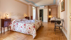 A bedroom with a bed, bedside tables, a chair, and a door leading to another room. - Room 'Aurora' at Francy House Termini Imerese (Termini Imerese)