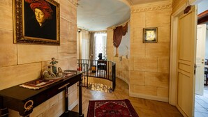 A hallway with a marble wall, a framed portrait, a statue, and a staircase. - Room 'Aurora' at Francy House Termini Imerese (Termini Imerese)