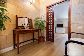 A room with a wooden dresser, a mirror, a potted plant, a bed, and a doorway leading to a kitchen. - Room 'Atena' at Francy House Termini Imerese (Termini Imerese)