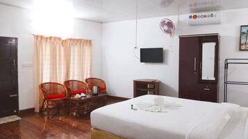 A hotel room with a bed, a desk with chairs, a TV, and a wardrobe.