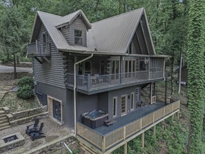 A two-story log cabin with a balcony, a hot tub, and a deck. - Riverfront Retreat, Sleeps 10・Water Views・Hot Tub (Townsend)
