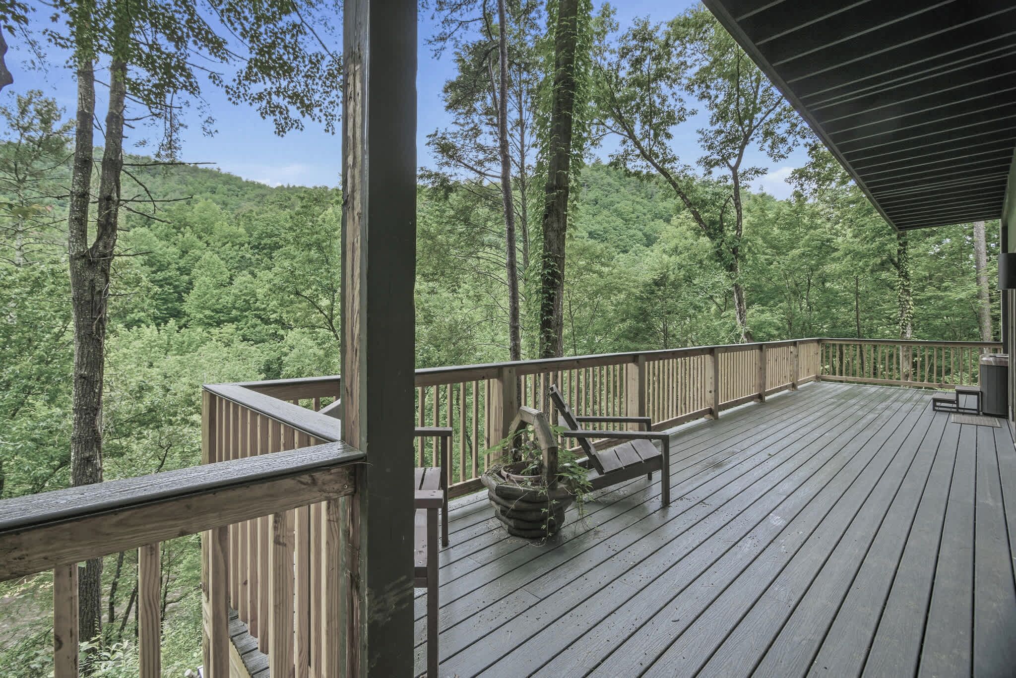 A wooden deck with a bench and a planter, surrounded by trees.
