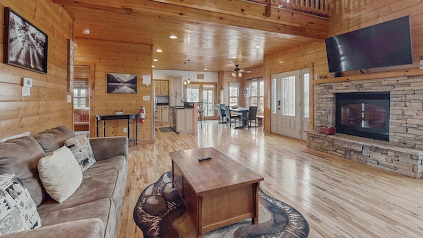 A spacious wooden cabin with a living area featuring a couch, a coffee table, and a fireplace. - Peaceful Retreat, Sleeps 8・Near Douglas Lake・Grill (Dandridge)