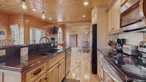 A spacious kitchen with wooden cabinets, a black countertop, stainless steel appliances, and a large island. - Peaceful Retreat, Sleeps 8・Near Douglas Lake・Grill (Dandridge)