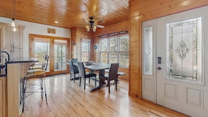 A wooden interior with a dining area, kitchen, and a large door with stained glass. - Peaceful Retreat, Sleeps 8・Near Douglas Lake・Grill (Dandridge)