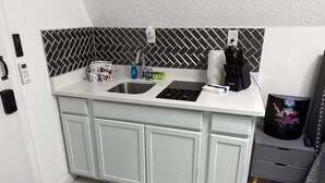Eine Küche mit weißer Arbeitsplatte, zwei Spülen und einer Küchenrückwand mit Fischgrätmuster.