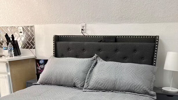 Ein Bett mit einer gesteppten, grauen Bettdecke, einer Fernbedienung und einem Schlüsselbund darauf.