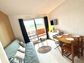 Ein kompakter Wohnbereich mit Balkon, Essbereich und einer Couch.
