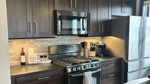 A modern kitchen with dark wood cabinets, stainless steel appliances, and a granite countertop. - Overlooks downtown Brevard with stunning mountain views! (Brevard)