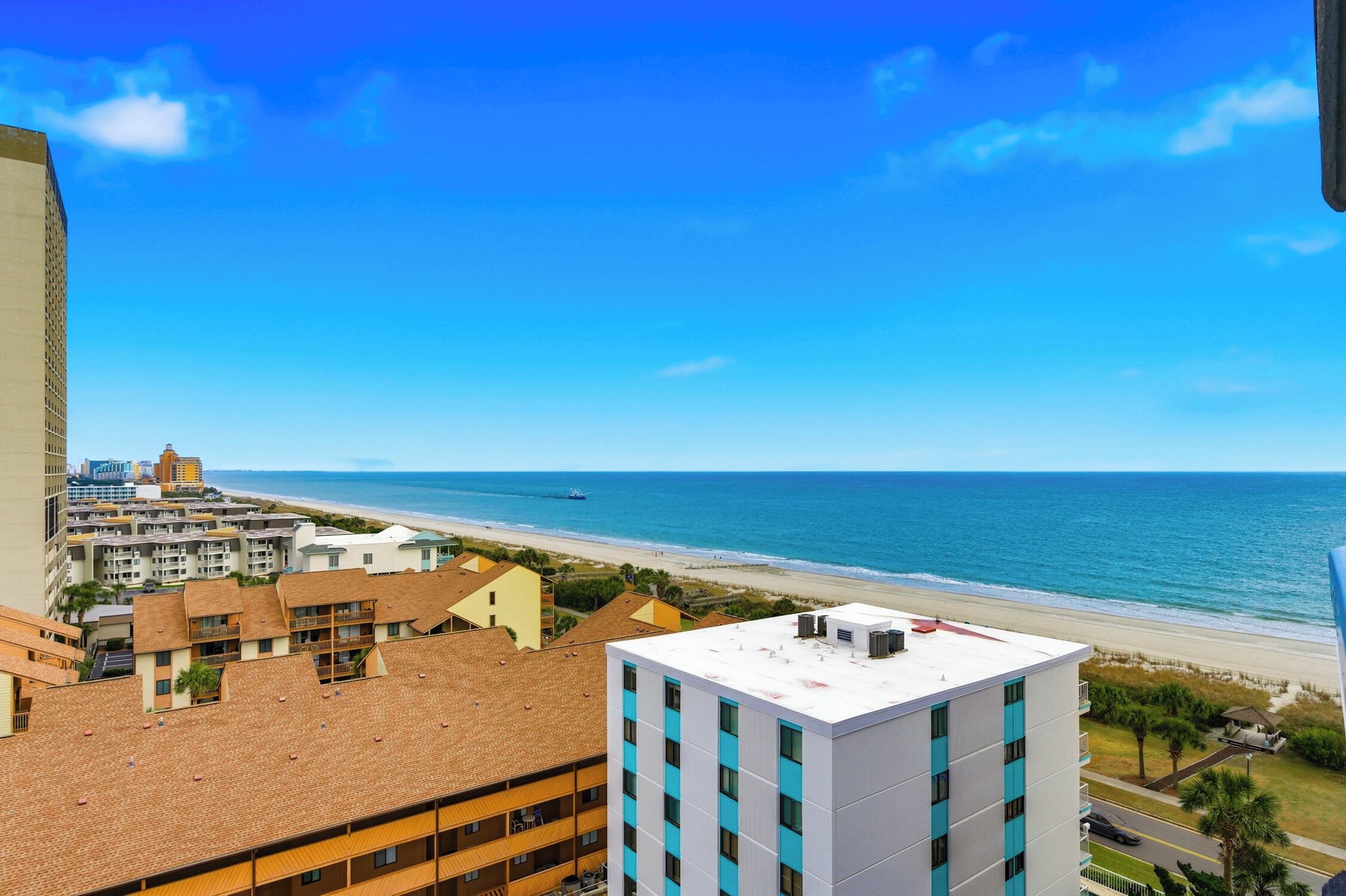 A coastal hotel with multiple buildings, a beach view, and a clear blue sky.
