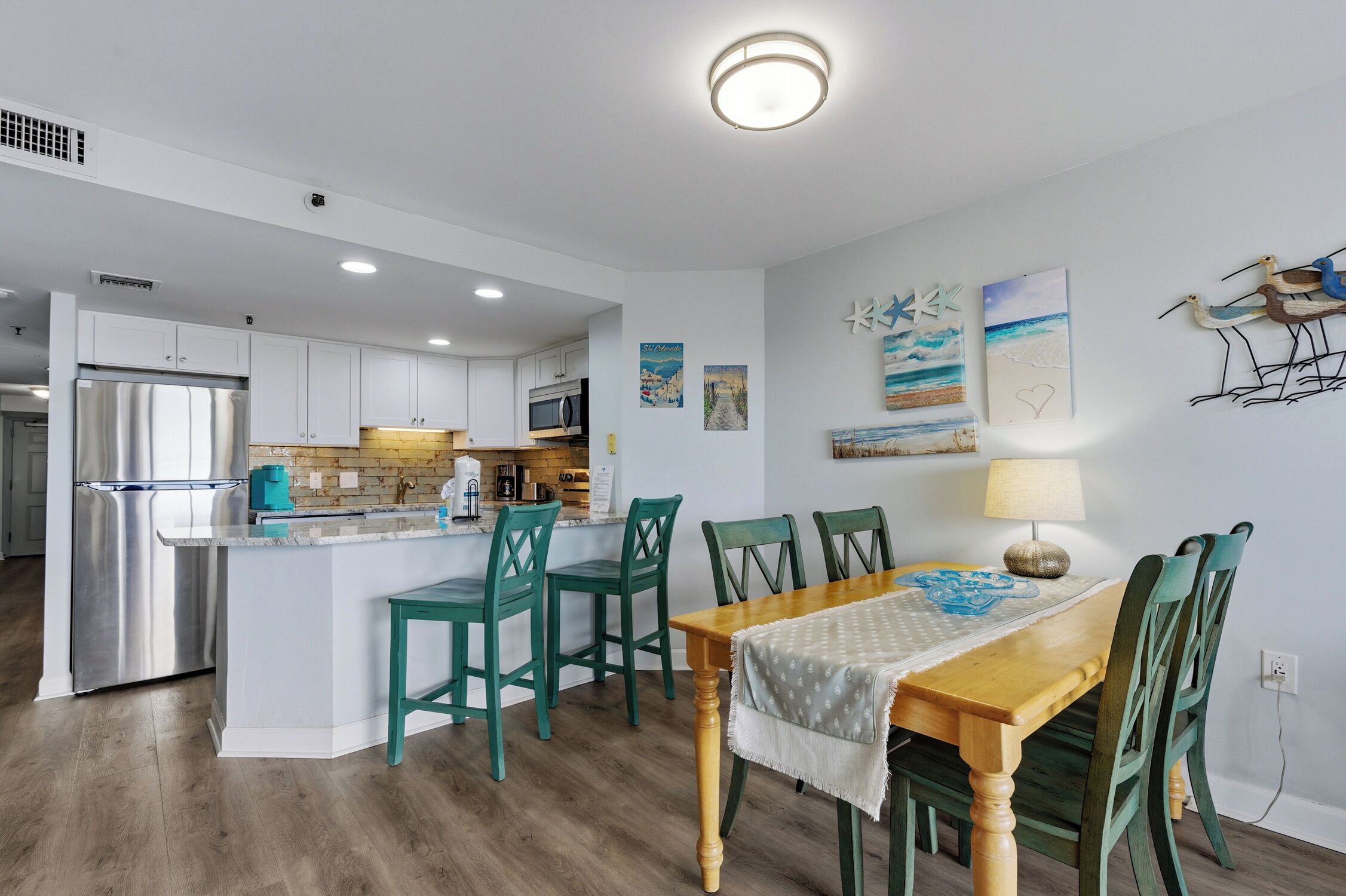 A modern kitchen with white cabinets, a stainless steel refrigerator, and a wooden island with bar stools.