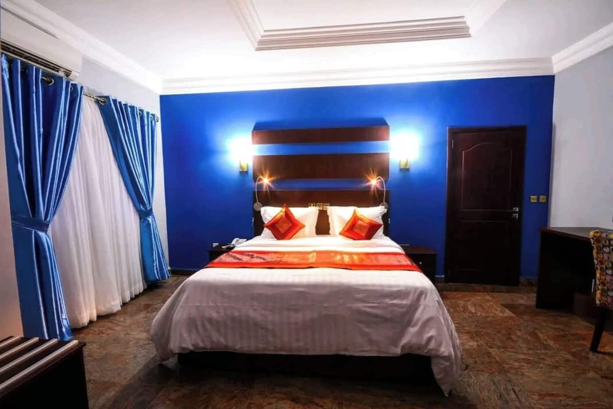 Une chambre d’hôtel avec un grand lit, des murs bleus et une tête de lit en bois.