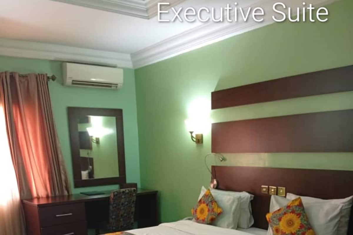 Une suite de luxe comprenant un grand lit, une commode, un miroir et un appareil de climatisation.