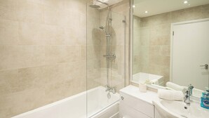 Ein modernes Badezimmer mit einer gläsernen Duschkabine, einer weißen Badewanne und einem Waschtisch mit Spiegel.