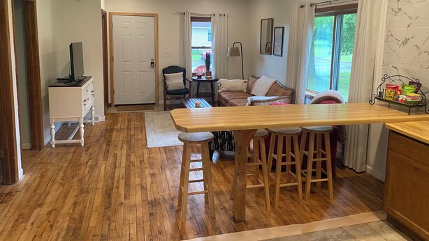 A cozy living area with a wooden floor, a sofa, a coffee table, and a TV on a cabinet. - Lovely 2-bedroom apartment in charming Kingsford (Kingsford)
