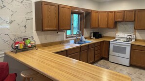 A kitchen with wooden cabinets, a white stove, and a marble backsplash. - Lovely 2-bedroom apartment in charming Kingsford (Kingsford)