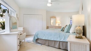Quarto com cama, cômoda, penteadeira e ventilador de teto.