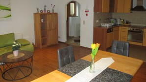 Una cocina moderna con armarios de madera, horno empotrado y comedor con mesa y sillas.