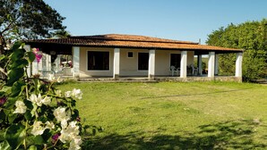 A two-story house with a tiled roof, a covered porch with white columns, and a grassy yard. - Casa de Campo Para so da Serra com Piscina e Vista (Iramaia)