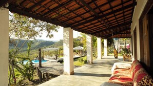 A covered outdoor area with a pool, lounge chairs, and a view of mountains. - Casa de Campo Para so da Serra com Piscina e Vista (Iramaia)