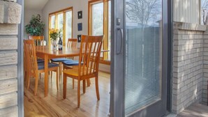 Ein modernes Interieur mit einer Schiebeglastür, die zu einem Essbereich mit Holzmöbeln und einer Hängeleuchte führt.