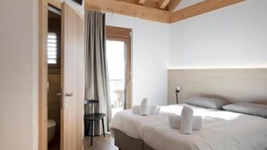 Un dormitorio moderno con techo de madera, una cama grande con almohadas, un televisor en la pared y vistas al exterior.