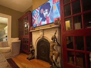 A living room with a fireplace, a television mounted above it, and a sofa.