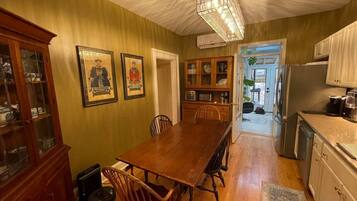A dining area with a wooden table and chairs, a cabinet with glass doors, and a chandelier.
