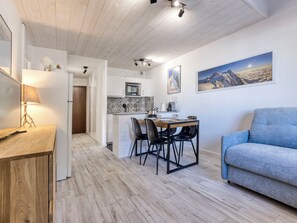 Ett modernt kök med en matplats, en soffa och en tavla på väggen.