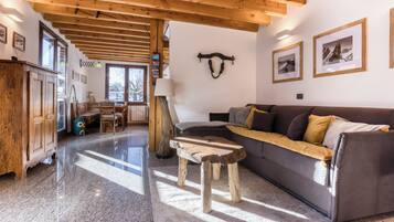 Un vaste espace de vie doté d’un plafond en bois, d’un canapé, d’une table basse et d’un coin repas avec des chaises et une table.