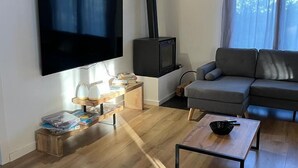 Een moderne woonkamer met een flatscreen televisie, een open haard, een bank en een salontafel.
