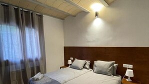 Een hotelkamer met een groot bed, twee nachtkastjes met lampen, een houten hoofdbord en een plafond met zichtbare balken.