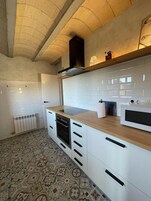 Una cocina moderna con armarios blancos, horno empotrado, microondas y encimera de madera.
