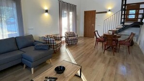 Een ruime woonkamer met een bank, een bijzettafeltje en een eethoek.