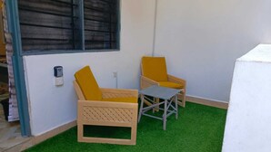 A small outdoor seating area with two yellow chairs and a small table on artificial grass. - Enjoyable bed & breakfast in charming Diani near the beach (DIANI)