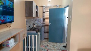 A compact kitchen with a stove, sink, and a blue door. - Enjoyable bed & breakfast in charming Diani near the beach (DIANI)